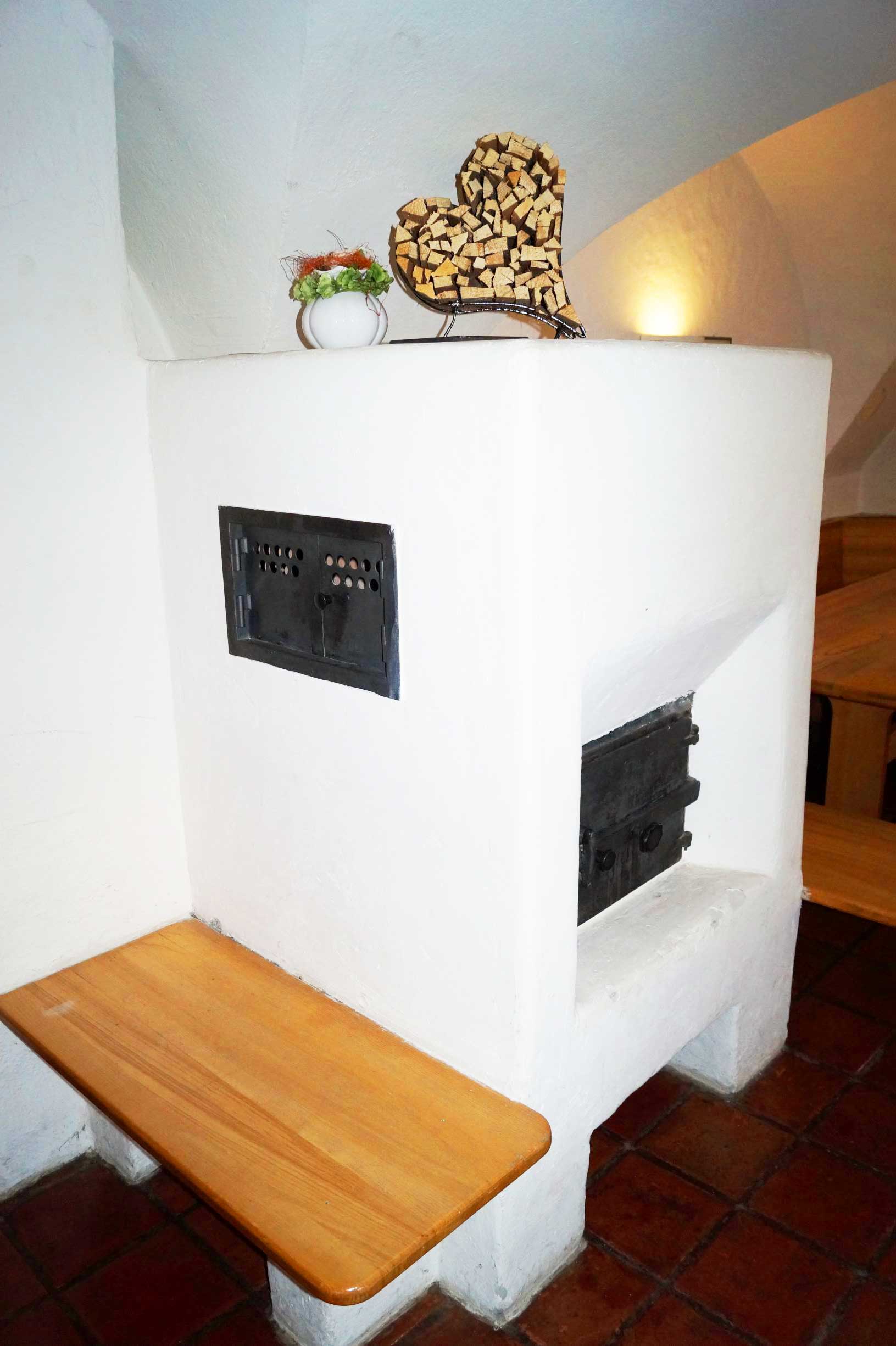 Kaminzimmer im Hostel Feldkirch für ca. 20 Personen mit traditionellem Kachelofen, mehreren Tischen mit Bänken und gemütlicher Atmosphäre für Spiele, Gespräche und entspannte Abende