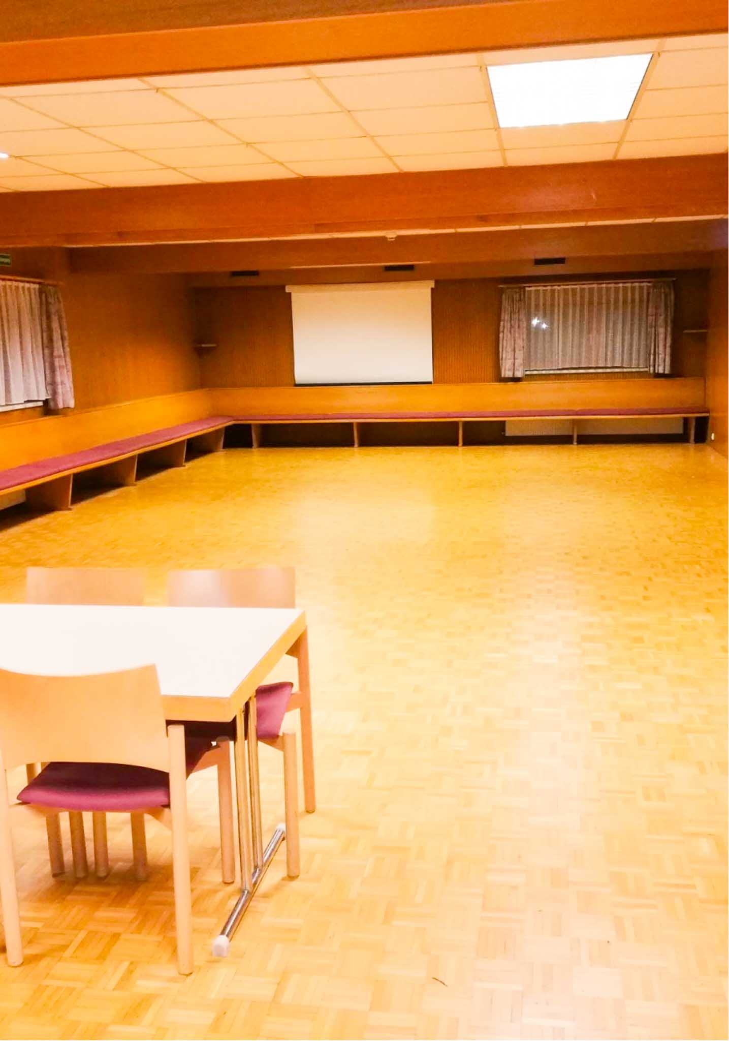 Großer Saal im Hostel Feldkirch für Veranstaltungen bis 140 Personen mit Parkettboden, Projektionsfläche, flexibler Bestuhlung und umlaufenden Sitzmöglichkeiten